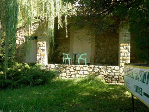 a patio with two chairs and a table in a stone wall at Auberge Les Sibourgs in Bourdeaux