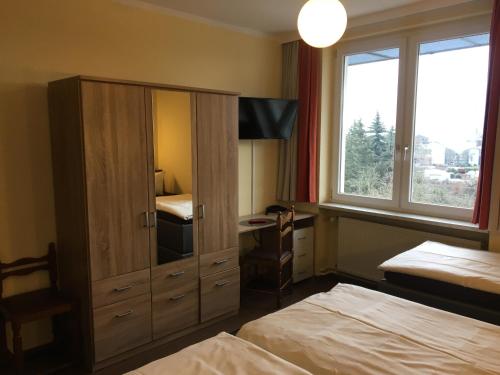 a bedroom with two beds and a cabinet with a desk at Hotel Sieme in Osnabrück