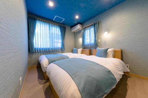 two beds in a room with blue ceilings and windows at 02 Resort Club -蒼SOU- in Fujikawaguchiko