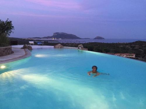 een persoon die zwemt in een groot blauw zwembad bij VILLA VISTA MARE INFINITY POOL in Marinella