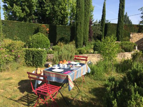 einem Tisch mit zwei roten Stühlen und einem Tisch mit Essen darauf in der Unterkunft B&B Chambre de Julie Le Jardin in Vaison-la-Romaine