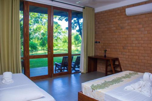 um quarto com 2 camas e uma porta para um pátio em Breezy Lake em Tissamaharama
