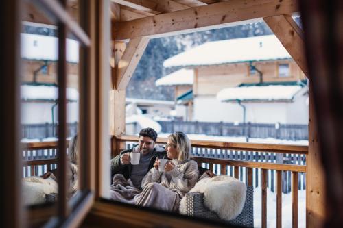 a man and woman sitting on a balcony in the snow at Feelfree Nature Resort in Oetz