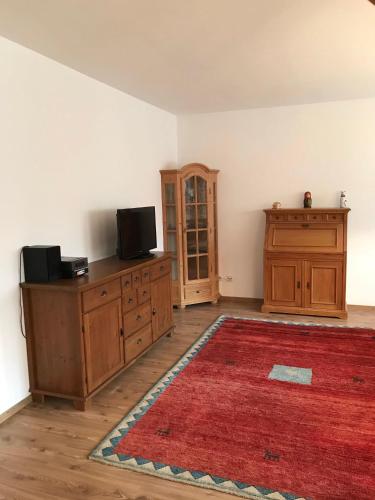 a living room with a tv on a cabinet and a red rug at Beim-Hofbauer in Tittmoning