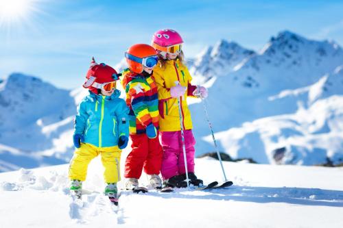 three children are standing in the snow on skis at Hotel Gailberghöhe in Kötschach