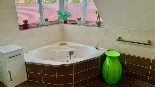 y baño con bañera y jarrón verde. en Fewo Am Krongut Bornstedt, en Potsdam