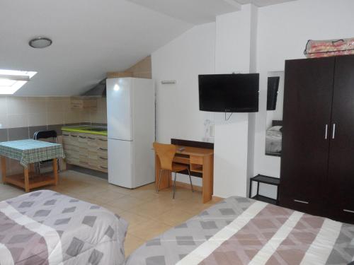 a bedroom with a bed and a desk and a tv at Hostal Via Del Caminante in Madrigalejo