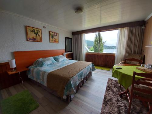 a bedroom with a bed and a table and a window at Complejo Pehuen Lago Lanalhue in Cañete