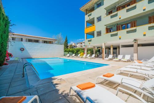 a swimming pool with lounge chairs next to a building at BRESSOL DELUXE Apartments in Port de Pollensa