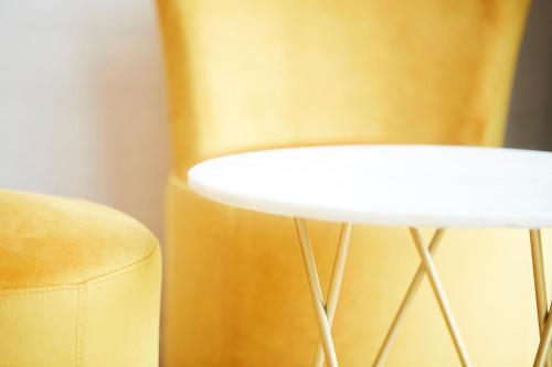 a white stool next to a yellow chair at B&B Armalot by Julia in De Panne