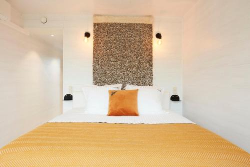 a bedroom with a bed with an orange pillow on it at B&B Armalot by Julia in De Panne