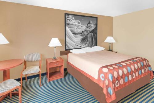 a hotel room with a bed and a table and chairs at Super 8 by Wyndham Marshalltown in Marshalltown