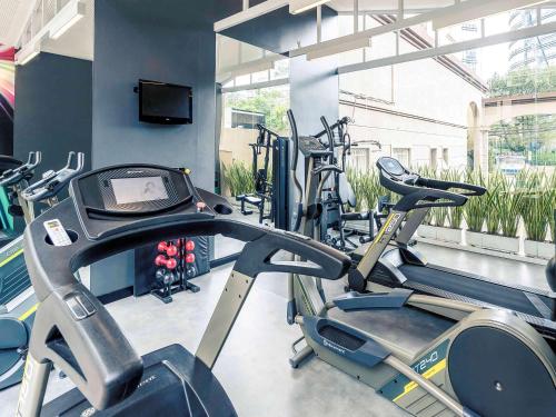 a gym with several cardio machines and a flat screen tv at Mercure Sao Paulo JK in Sao Paulo