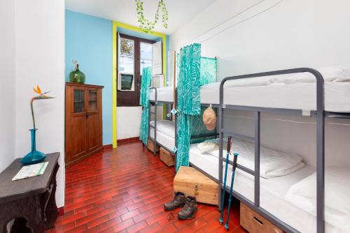 a room with three bunk beds and a red tile floor at Patio Hostel in La Laguna