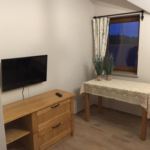 a living room with a flat screen tv and a table at Folwark Pod Dębem in Nowa Karczma