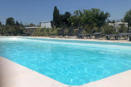 una piscina con sillas y agua azul en Gîte Pierre Blanche, en Visan