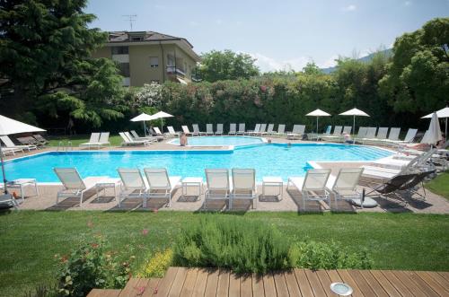 a pool with chairs and umbrellas in a yard at Hotel Luise in Riva del Garda