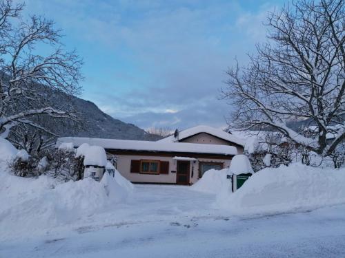 a house covered in snow with trees and bushes at Ferienwohnungen Angermaier in Flattach