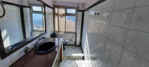 ein Bad mit einem Waschbecken, einem WC und einem Fenster in der Unterkunft Yuma D Homestay in Darjeeling