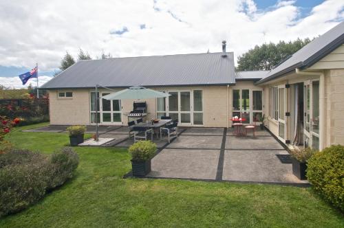 a house with a patio and an umbrella at Ruapehu Country Lodge in Ohakune