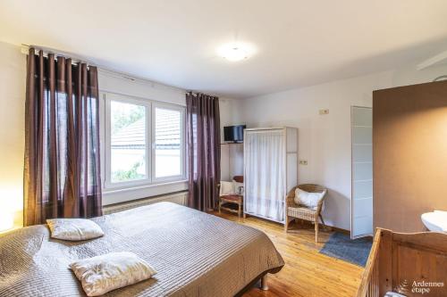 斯圖蒙的住宿－Les Bastinettes，一间卧室设有一张大床和一个窗户。