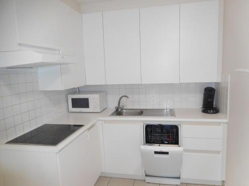 a white kitchen with a sink and a microwave at Bella Plaza in De Panne