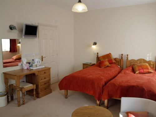 a bedroom with two beds and a desk and a television at The Reading Rooms in Haydon Bridge