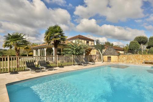 una piscina con sillas y una casa en Hotel Le Mas de Castel - Piscine chauffee, en Sarlat-la-Canéda