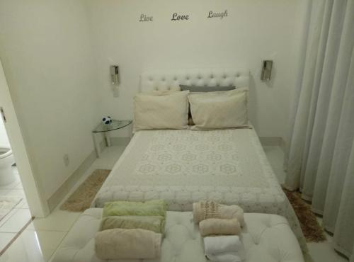 a white bedroom with a large bed with a couch at Aconchegante apto em localização privilegiada in Cuiabá