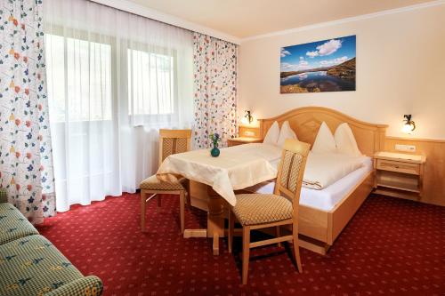 ein Hotelzimmer mit einem Bett, einem Tisch und Stühlen in der Unterkunft Jagdhof in Großarl
