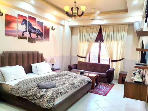 a bedroom with a bed and a couch and a chair at Luxurious Landing Apartments & Suites Bahria Town in Rawalpindi