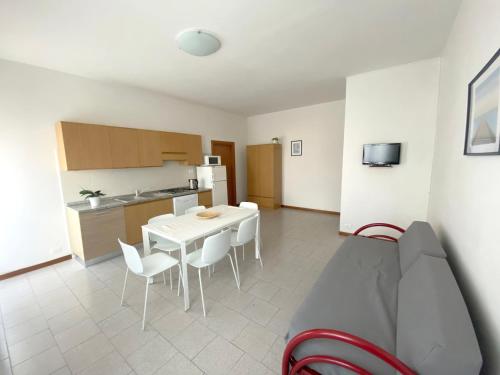Dainese Apartments, Casa Ester في ليدو دي يسولو: مطبخ وغرفة طعام مع طاولة وكراسي