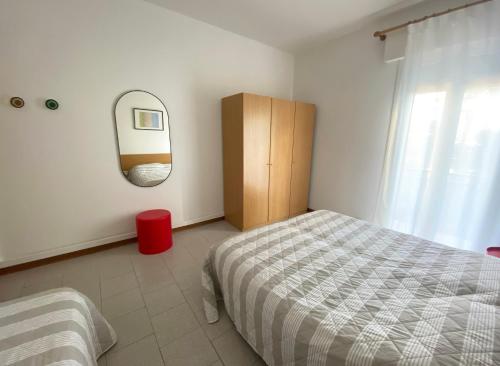1 dormitorio con cama y espejo en la pared en Dainese Apartments, Casa Ester, en Lido di Jesolo