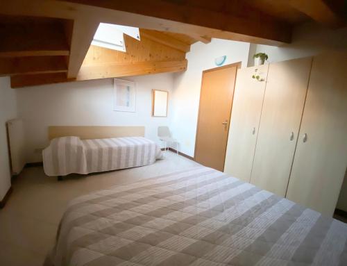 Dainese Apartments, Casa Abigail في ليدو دي يسولو: غرفة نوم بسرير كبير وسقوف خشبية
