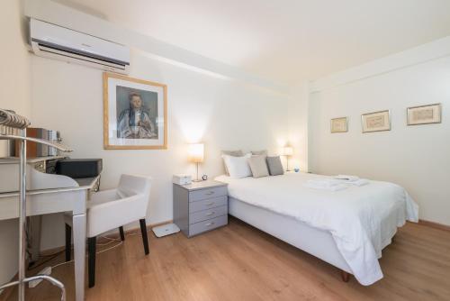 a white bedroom with a bed and a desk at Syntagma Spa with Acropolis View in Athens