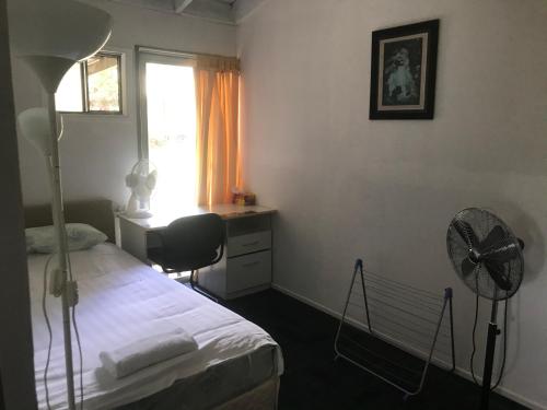 a bedroom with a bed and a desk and a fan at Convenience house in Nerang with Private room in Gold Coast