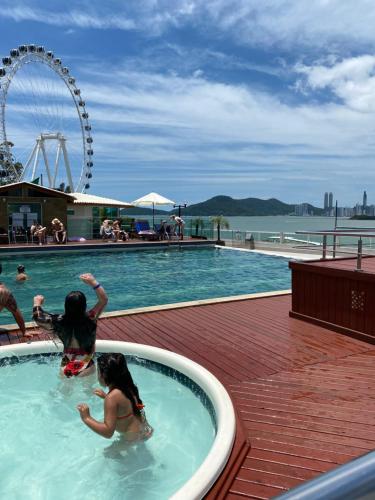 two girls playing in a swimming pool at a resort at "Conforto e Bem Estar" Próximo da praia in Balneário Camboriú