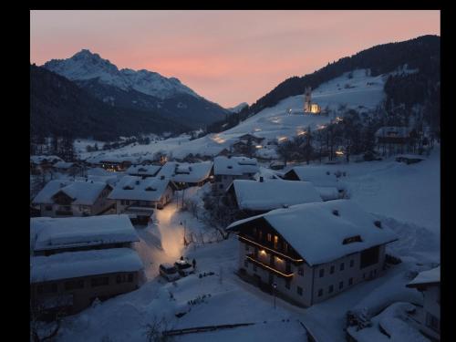 a village covered in snow at sunset with the mountains at Residence Tamperhof in San Candido