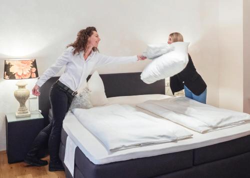 two women jumping on top of a bed at Boutique Hotel Friesinger in Kressbronn am Bodensee