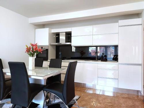 a kitchen with white cabinets and a table and chairs at Deluxe Apartment MyPlace in Osijek