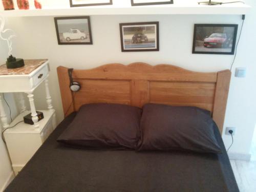 a bed with a wooden headboard in a bedroom at APPART MER CALME ET ENSOLEILLEE in Le Grau-du-Roi