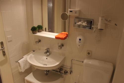 a white bathroom with a sink and a toilet at Hotel Rosmarin in Bad Zwischenahn