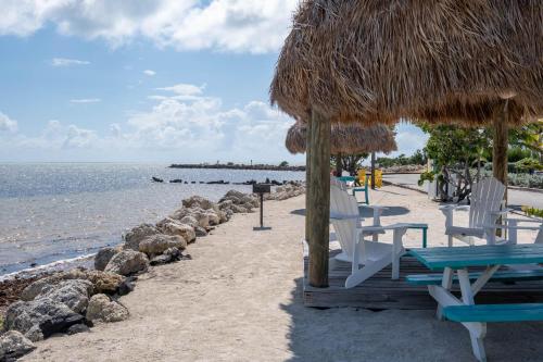 a beach with chairs and a straw umbrella and the ocean at SEA MIST - Oceanfront-Lake-Kayak-Paddleboard-Bike in Key Largo