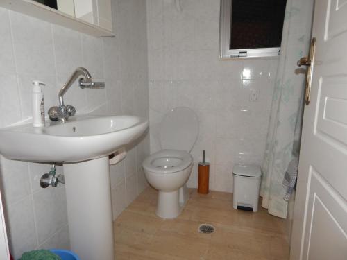 a white bathroom with a toilet and a sink at Tripoli Apartments and Rooms in Tripoli