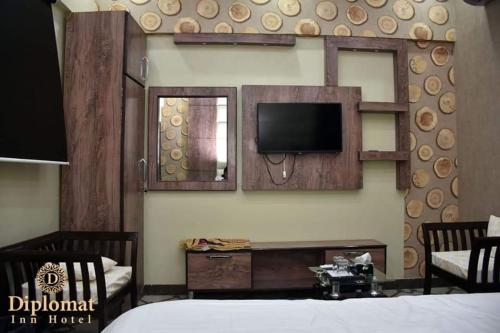 Habitación con cama y TV en la pared. en Diplomat Inn Hotel, en Karachi
