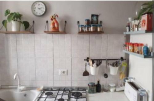 a kitchen with a stove and a clock on the wall at LE ORIGINI casa in borgo tipico lucano in Trivigno