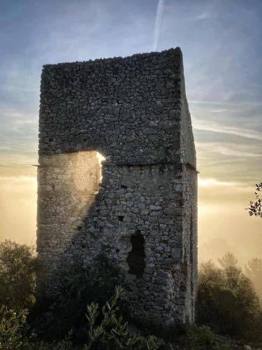 an old stone building with a sunset in the background at Hostel Le Diablotin in Saint-Jean-de-Fos