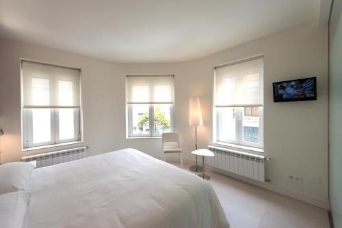 a bedroom with a large white bed and windows at Hotel Boreal Viento Norte in Burgos