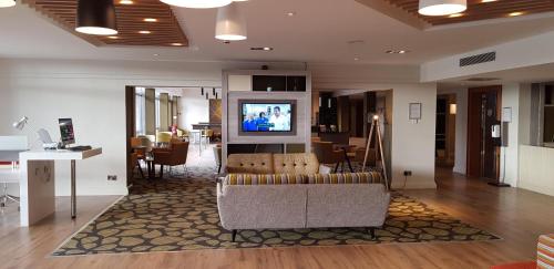 a living room with a couch and a television at Holiday Inn Luton South - M1, Junction 9, an IHG Hotel in Luton