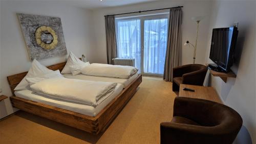 a bedroom with a bed and two chairs and a television at Ferienhaus Wetterstein in Grainau